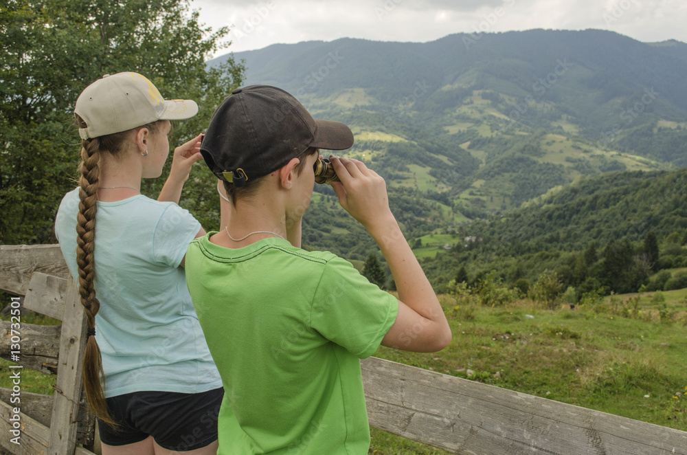 Girl and boy looking into the distance on a beautiful mountain landscape
