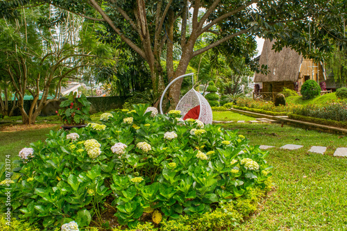 Obraz na płótnie Landscape design of relax yard with hydrangea flowerbed and a chair w salonie