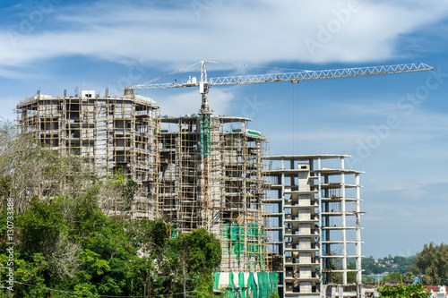 Large crane and building construction site against blue sky and
