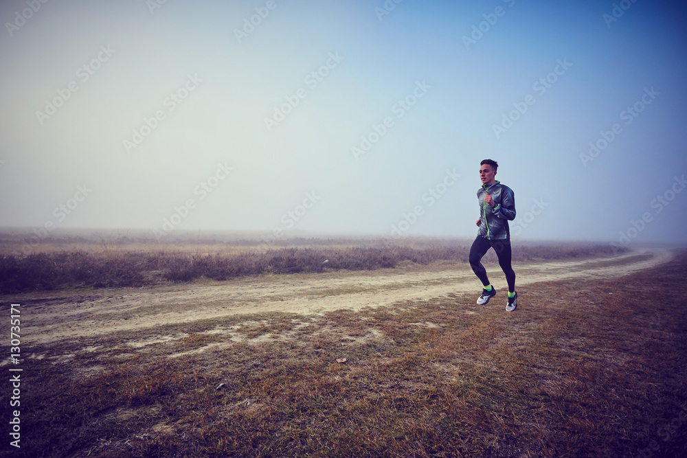 Ragazzo si allena su strada sterrata nella nebbia Ragazzo si allena su strada sterrata nella nebbia