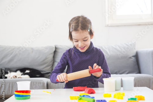 Little girl rolling out modeling clay photo