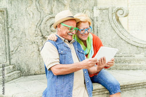 Senior happy couple watching videos on tablet computer device photo