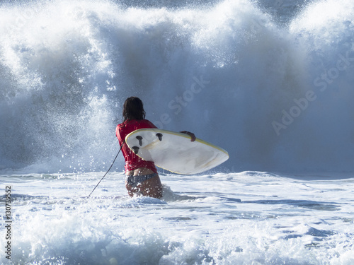 Photography Girl practicing in the waves of the Atlantic ocean surfing, in f