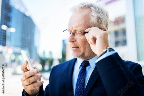 senior businessman with smartphone in city