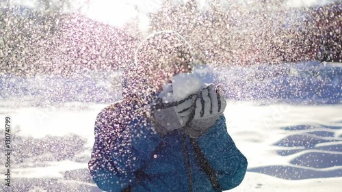 happy child having fun in winter Park on a Sunny day.Blows the snow from the palm of