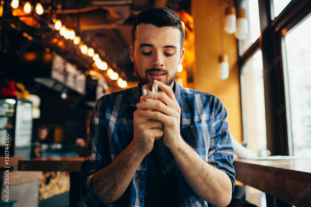 Young man is sitting in the restaurant and tasting a warm drink. Young man is sitting in the restaurant and tasting a warm drink.