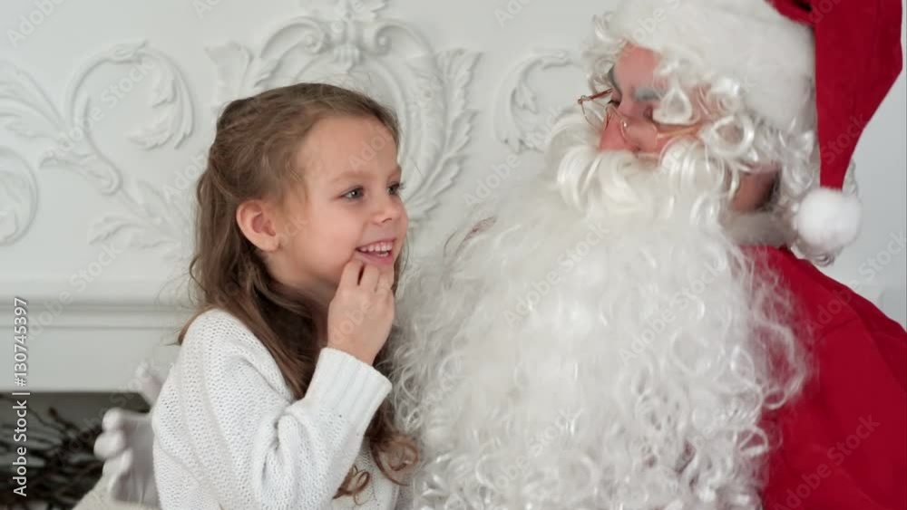 Sweet little girl on Santa Claus lap telling him what she wants for Christmas Sweet little girl on Santa Claus lap telling him what she wants for Christmas