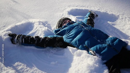 the baby lies on snow and making a snow angel in slowmotion