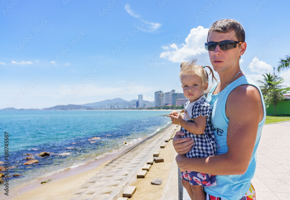 Dad and daughter playing on the promenade by the sea. young man, little girl