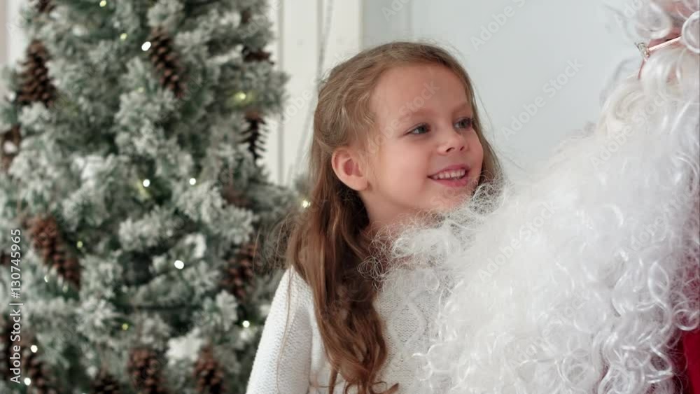 Surprised little girl checking upon Santa beard Surprised little girl checking upon Santa beard