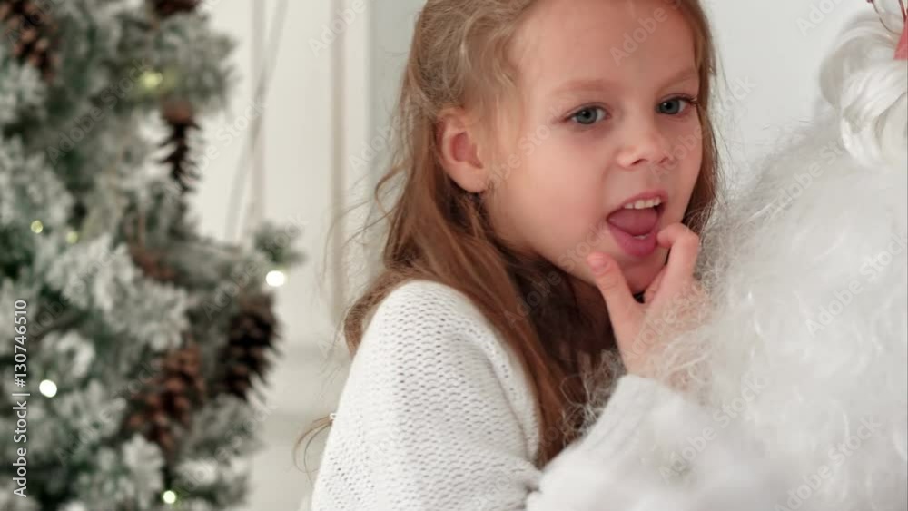 Smiling and shy girl sharing her Christmas dreams with Santa Smiling and shy girl sharing her Christmas dreams with Santa
