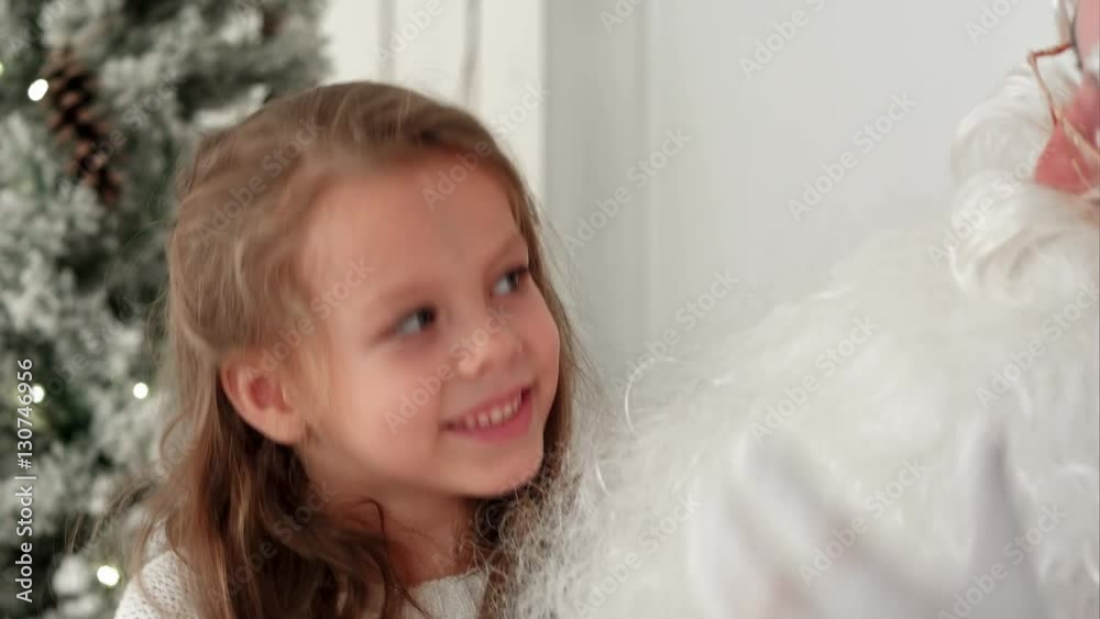 Cute little girl singing Christmas song together with Santa Claus Cute little girl singing Christmas song together with Santa Claus