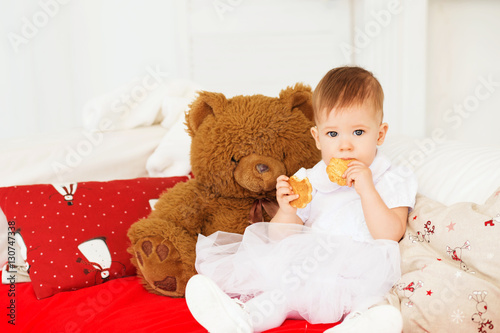 beautiful baby girl with a soft brown teddy bear in the interior