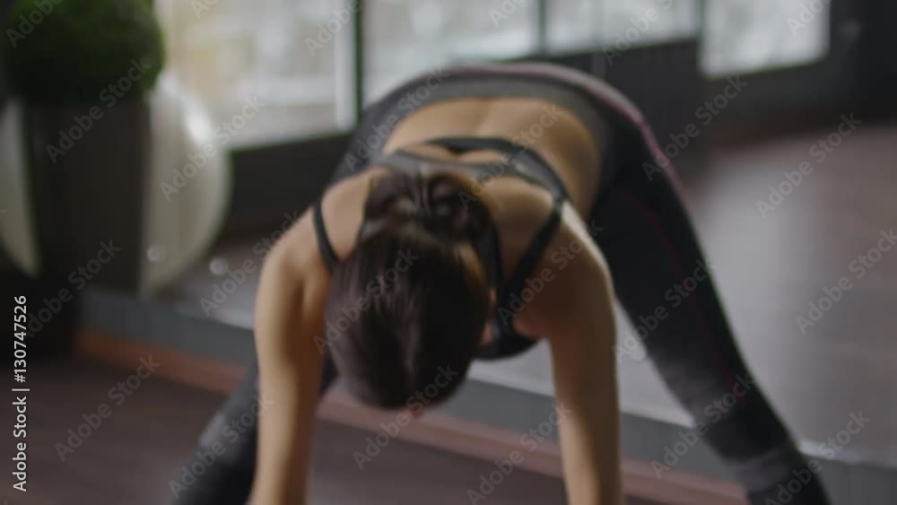 Pregnant woman bending torso forward and stretching her arms and then raising up one hand and holding thumb and index finger together while exercising in studio Pregnant woman bending torso forward and stretching her arms and then raising up one hand and holding thumb and index finger together while exercising in studio