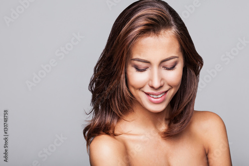 Studio portrait of a beautiful young woman with long brunette hair. Pretty spa model girl with perfect fresh clean skin. Youth and skin care concept