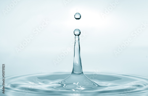 Water splash isolated on blue background. Water drop. Collision of two drops of water