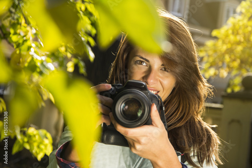 Taking a quick photo at the park! Young woman using her camera at the park.