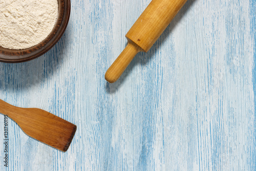 Ingredients for dough. Flour, rolling pin on a blue scratched background. Top view. Flat lay. Mockup for menu or recipe.