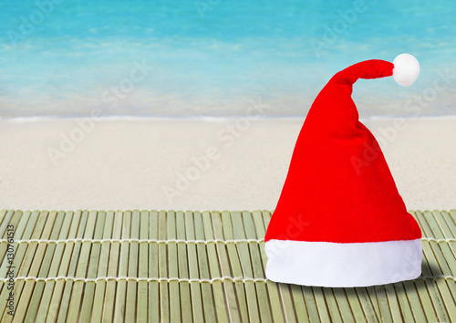 Red hat of Santa Claus and blue ocean, sandy beach on background photo