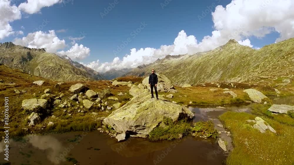aerial view of young single man standing on rock in mountain lake landscape. water reflection. aerial view of young single man standing on rock in mountain lake landscape. water reflection.