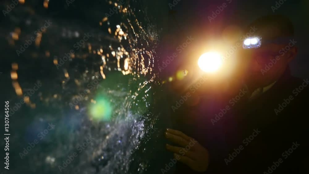 scientist researching ice inside glacier cave tunnel using flashlight. climate change background.