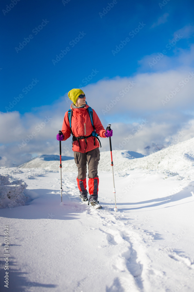 Girl with backpack walking on snow in the mountains.