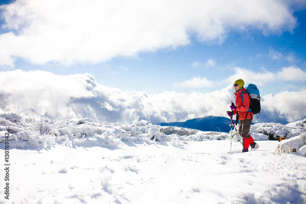 Girl with backpack walking on snow in the mountains.