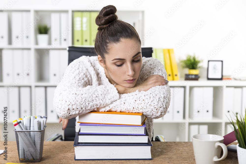 Woman is about to fall asleep on a pile of books Woman is about to fall asleep on a pile of books