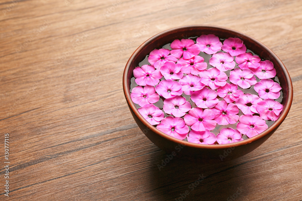Bowl with water and pink flowers on wooden background Bowl with water and pink flowers on wooden background