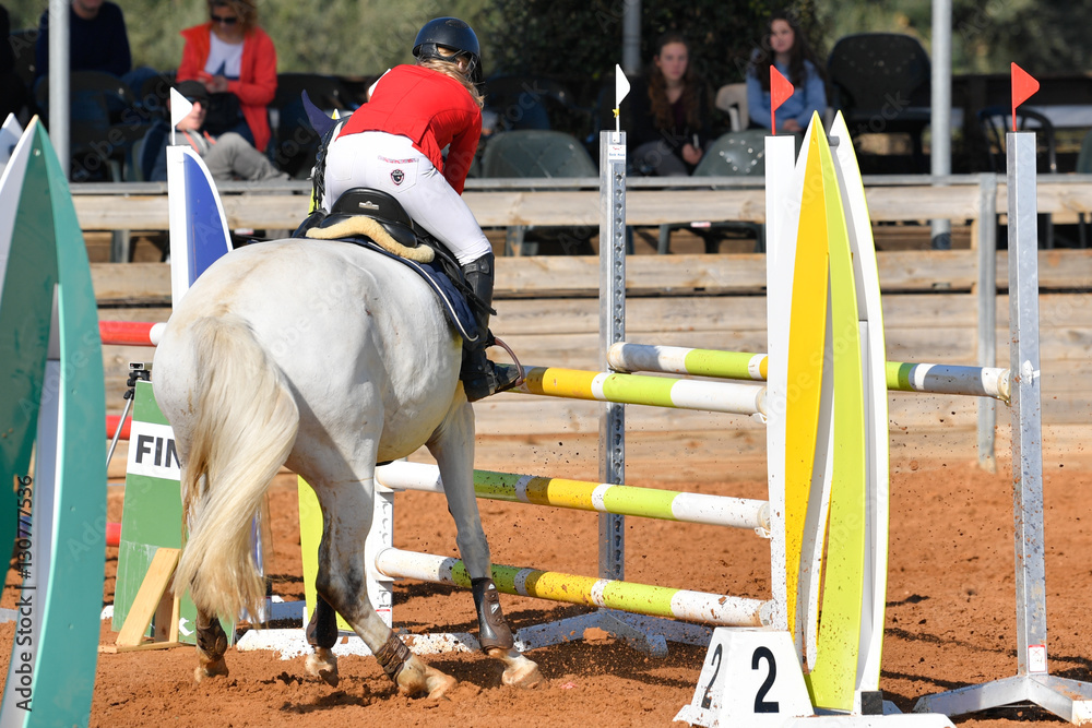 Rider on horse jumping over a hurdle during the equestrian event Rider on horse jumping over a hurdle during the equestrian event