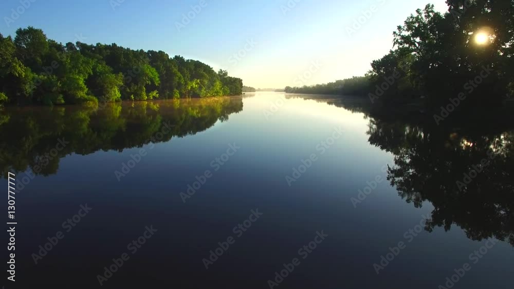 Sunrise escapes from the shadows over tranquil river surface.
Sunrise escapes from the shadows over tranquil river surface.