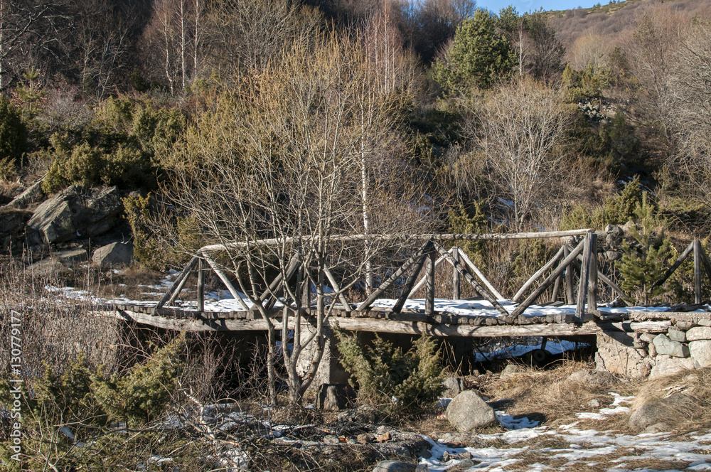 Wooden bridge over small mountain river in winter