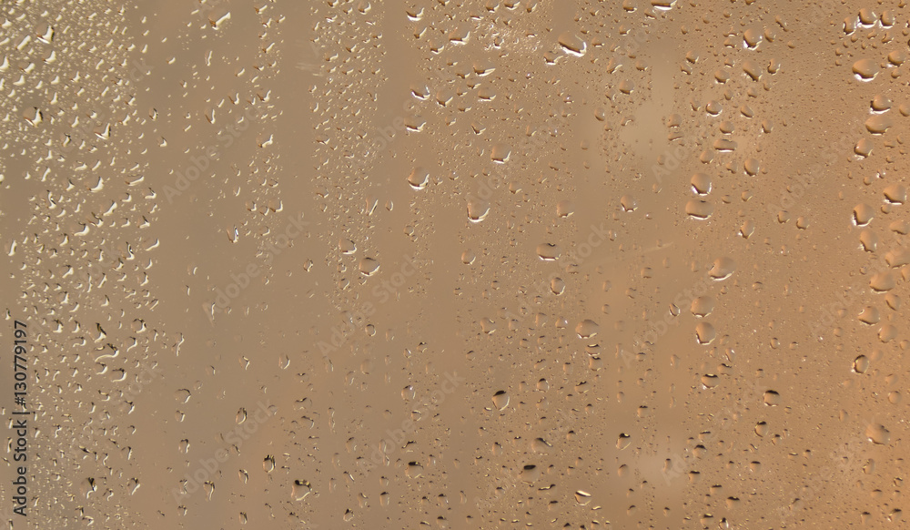 Water drops on a wet window with a gold colored defocused background abstract. Water drops on a wet window with a gold colored defocused background abstract.