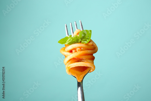 Murais de parede Fork with tasty pasta and basil on color background, close up view