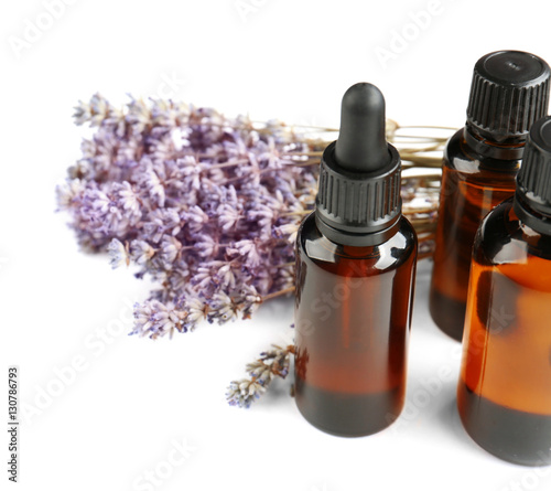 Bottles with essential oil and lavender on white background