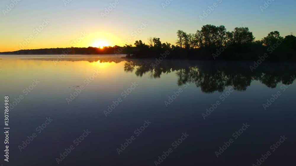 Flying low over foggy river at dawn. Geese swimming peacefully on the still water’s surface. Flying low over foggy river at dawn. Geese swimming peacefully on the still water’s surface.