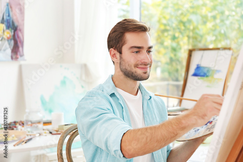 Young male artist painting ...