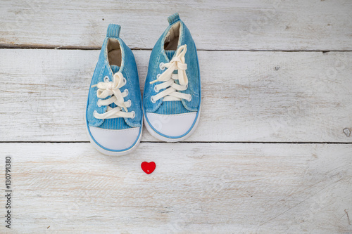 small baby blue sneakers on a white wooden background. baby shoe