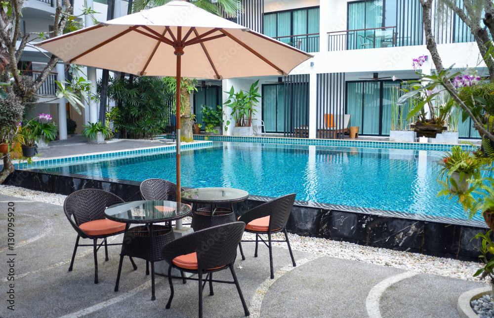 Fototapeta premium Relaxing rattan chairs beside swimming pool