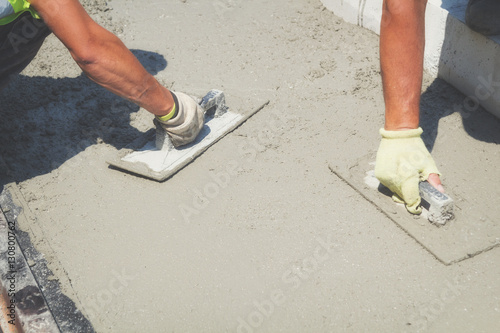 Construction workers leveling concrete pavement.