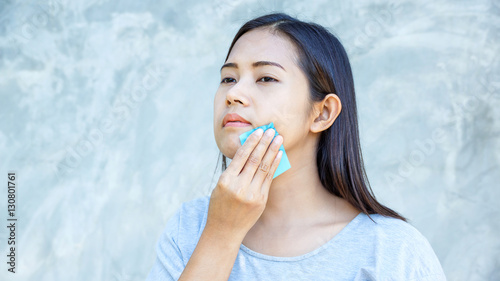 Billede på lærred Women use oil remover paper on her face.