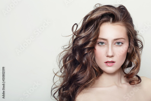 Portrait of young beautiful girl with clear skin and long healthy curly hair