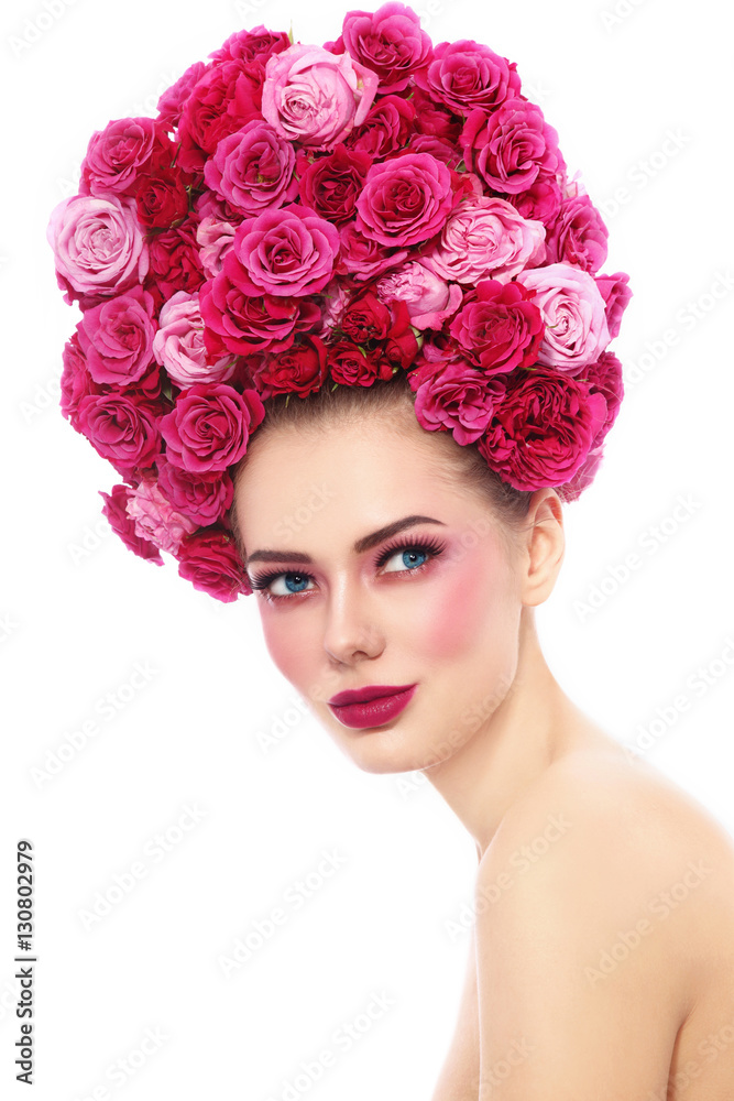 Young beautiful woman with stylish make-up in fancy vintage style wig of pink roses looking upwards, over white background
