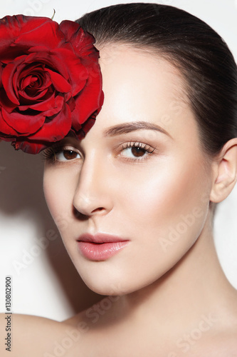 Portrait of young beautiful woman with glowing make-up and red rose