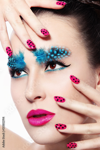 Close-up portrait of young beautiful woman with fancy feather eyebrows and dot manicure