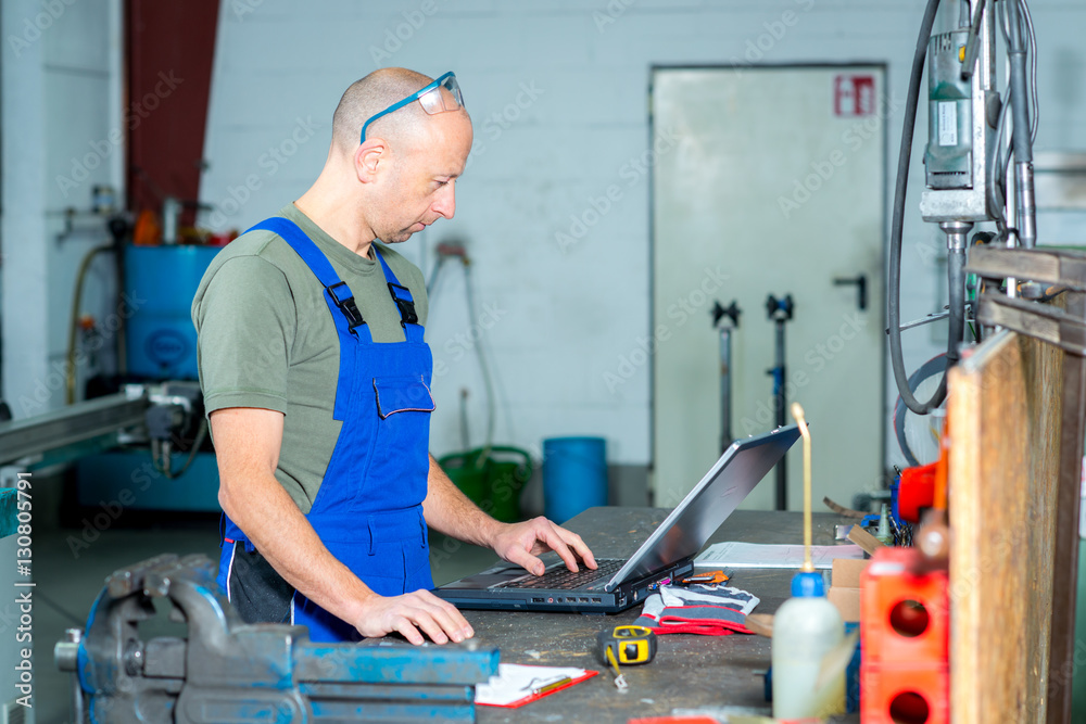 worker in factory on work bench with computer worker in factory on work bench with computer
