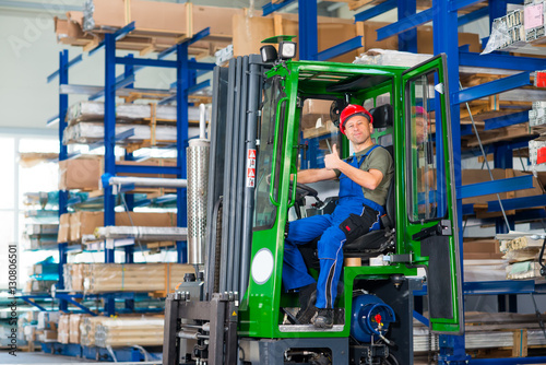 worker in factory in lift truck with thumb up