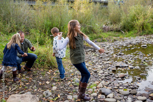 Siblings Throwing Rocks In River Together