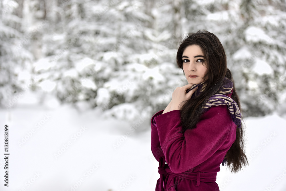 Girl in a red coat and headscarf on the background of snow-covered trees Girl in a red coat and headscarf on the background of snow-covered trees