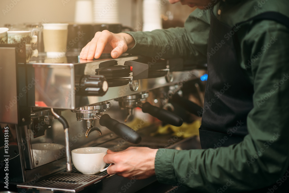 Male waiter standing against coffee machine Male waiter standing against coffee machine